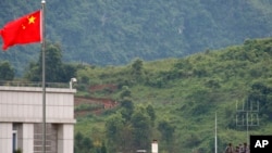 FILE - Myanmar government troops stand on a rooftop on the Myanmar side, near a Chinese flag from the Chinese border town of Nansan in southwestern China's Yunnan province, Sunday, Aug 30, 2009