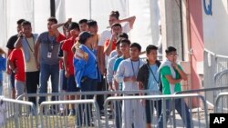 FILE - Children line up to enter a tent at the Homestead Temporary Shelter for Unaccompanied Children in Homestead, Fla., April 19, 2019. Immigrant advocates say the U.S. government is allowing migrant children to languish in “prisonlike conditions” instead of releasing them.