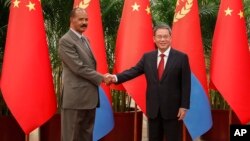 Chinese Premier Li Qiang, right, and Eritrean President Isaias Afwerki shake hands as they attend a meeting at the Great Hall of the People in Beijing, May 15, 2023. 
