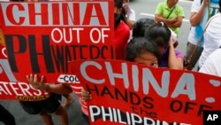 FILE - Protesters display placards during a rally at the Chinese consulate in the financial district of Makati city, east of Manila, Philippines, Nov. 12, 2015.
