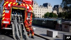 A firefighter checks his phone as he rests near the Notre Dame cathedral, in Paris, April 19, 2019.