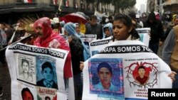 Relatives and friends hold banners with images of some of the 43 missing students of Ayotzinapa College Raul Isidro Burgos as they march in Mexico City to mark the first anniversary of the students' disappearance, Sept. 26, 2015.