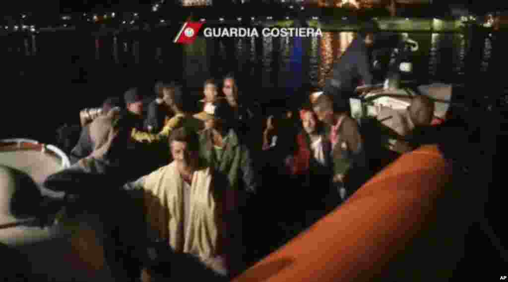 This image from video shows survivors of a ship that sank being transported on an Italian Coast Guard vessel as it arrives at port, Lampedusa, Italy, Oct. 3, 2013. (Italian Coast Guard)