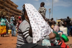 A woman and a child wait for a taxi at the old taxi park in Kampala, Uganda, on June 4, 2020, the first day of the reopening of public transport.