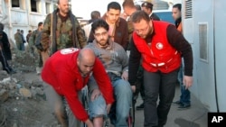 Palang Merah Suriah membantu seorang warga mengungsi dari kota Homs yang dikuasai pemberontak, Minggu (9/2).