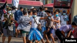 A military supporter points a sharp object as he confronts pro-democracy protesters during a military support rally in Yangon, Myanmar, Feb. 25, 2021. 