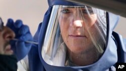 បុគ្គលិកសុខាភិបាលម្នាក់កំពុងយកសំណាកពីបុរសម្នាក់ដែលស្ថិតក្នុងរថយន្ត ដើម្បីធ្វើតេស្តរកជំងឺកូវីដ ១៩ នៅទីក្រុង Salt Lake រដ្ឋ Utah កាលពីថ្ងៃទី៥ ខែវិច្ឆិកា ឆ្នាំ២០២០។