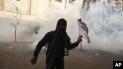 A protester runs away from tear gas during clashes with security forces near the Interior Ministry in Cairo, February 4, 2012.