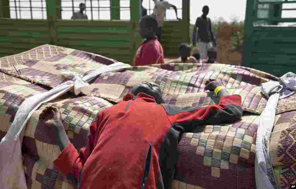 Refugees who fled the recent violence in South Sudan and crossed the border into Uganda rest and await transportation from a transit center in Koboko, Jan. 6, 2014.