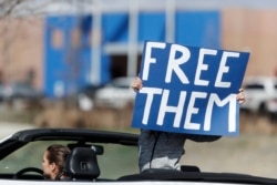 A protester wields a sign as anti-government groups call for the release of detained immigrants at the GEO Detention Center, because of the coronavirus, April 3, 2020, in Aurora, Colo.