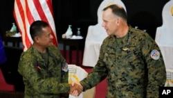 US Marine Corp MGEN Eric Austin, US Exercise Director Representative, right, and Philippine Army MGEN Marvin Licudin, Philippine Exercise Director shake hands at the opening ceremonies of a joint military exercise called "Balikatan," April 11, 2023, in Quezon City, Philippines. 