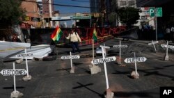 A woman holds a national flag as she stands at a barricade during a protest against the reelection of President Evo Morales, in La Paz, Bolivia, Oct. 28, 2019.