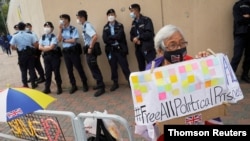 Pro-democracy supporter holds a sign calling for the release of all political prisoners outside Tin Shui Wai police station in Hong Kong, March 22, 2021.