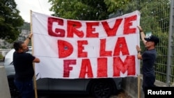Thierry Paysant, security worker and firefighter at the Pasteur hospital, and Christophe, caregiver at the Pasteur hospital, hold a banner reading 'Hunger strike' to protest against France's COVID restrictions, in Nice, France, Sept. 15, 2021. 