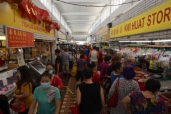 FILE - Customers visit a wet market to buy food in Singapore on April 4, 2020, with some people wearing facemasks due to concerns over the spread of the COVID-19 coronavirus.