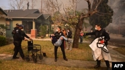 Police officers evacuate an elderly resident from her home during the Eaton Fire in Altadena, California, on Jan. 8, 2025.