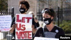 FILE - Protesters gather outside of the Georgia State Capitol in Atlanta to protest a bill which would place tougher restrictions on voting in Georgia, March 4, 2021. 