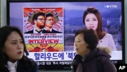 People pass a TV screen showing a news report on Sony Picture's 'The Interview,' at the Seoul Railway Station in South Korea.