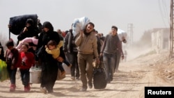 People flee the rebel-held town of Hammouriyeh, in the village of Beit Sawa, eastern Ghouta, Syria, March 15, 2018.