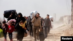 People walk with their belongings as they flee the rebel-held town of Hammouriyeh, in the village of Beit Sawa, eastern Ghouta, Syria, March 15, 2018.