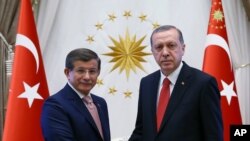 FILE - Turkish President Recep Tayyip Erdogan, right, and Prime Minister Ahmet Davutoglu shake hands as they pose for a photograph during a final farewell in Ankara, May 19, 2016.