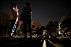 FILE - Patients with kidney disease and their relatives wait on the street for the return of electricity, in front of a dialysis center during a blackout, in Maracaibo, Venezuela, April 13, 2019.
