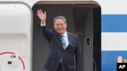 El primer ministro chino, Li Qiang, saluda a los miembros de los medios a su llegada para reuniones trilaterales en el aeropuerto de Seúl en Seongnam, Corea del Sur, el domingo 26 de mayo de 2024.