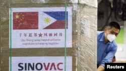 FILE - A worker unloads a box of Sinovac Biotech's CoronaVac vaccines from a Chinese military aircraft at Villamor Air Base in Pasay, Metro Manila, Philippines, Feb. 28, 2021.