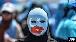 A demonstrator wearing a mask painted with the colours of the flag of East Turkestan and a hand bearing the colours of the Chinese flag attends a protest of supporters of the mostly Muslim Uighur minority and Turkish nationalists to denounce China's treat