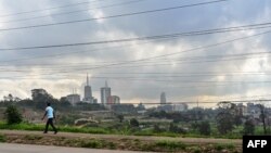 FILE - A section of Nairobi's city scape is seen May 16, 2019, through a crisscross of electrical lines as a man on his morning commute walks along Mbagathi Way in the Kenyan capital's southern sector.