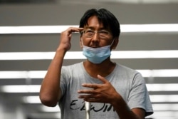 Yuki Kitazumi, a Japanese freelance journalist detained in Myanmar in mid-April and accused of spreading fake news criticizing the military coup, gestures to speak to reporters as he arrives at Narita International Airport, Japan, May 14, 2021.
