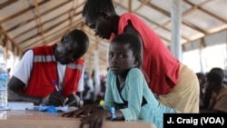 FILE - South Sudanese girl waits for her mother to finalize their paperwork in the Imvepi refugee settlement’s processing center in Arua, Uganda, March 31, 2017.