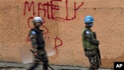 U.N. peacekeepers walk next to a wall with a graffiti in support of presidential candidate Michel Martelly at the Petionville neighborhood in Port-au-Prince, 12 Dec 2010