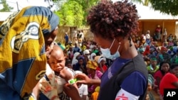 A Medecins Sans Frontieres (Doctors Without Borders) staff member measures a child's upper arm circumference to check for malnutrition in Meluco, in the northern Mozambican province of Cabo Delgado, Feb. 19, 2021, in this photo made available by MSF. 