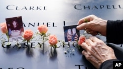 FILE - Mourners place flowers and pictures in the name cutout of Kyung Hee (Casey) Cho at the National September 11 Memorial and Museum, Sept. 11, 2020, in New York. 