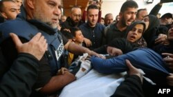 (FILES) The widow (R) of Hamza Wael Dahdouh, a journalist with the Al Jazeera television network, and his father Al Jazeera's bureau chief in Gaza, Wael Al-Dahdouh (L) mourn over his body during his funeral, after he was killed in a reported Israeli air s