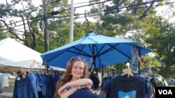 Ellie Heath stands next to some of her designs - made of recycled fabrics and adorned with her distinctive artistic touch (Photo: F. Elmasry / VOA) 