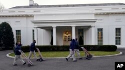 Workers walk with hand trucks past the West Wing of the White House, as offices in the White House complex are being packed up and moved out, Friday, Jan. 15, 2021, in Washington. (AP Photo/Gerald Herbert)