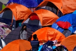 FILE - Tents used by migrants seeking asylum in the United States line an entrance to the border crossing, March 1, 2021, in Tijuana, Mexico.