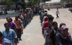 FILE - Impoverished Indians stand in queues to receive free food in Hyderabad, India, March 27, 2020.