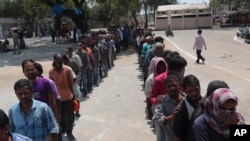 FILE - Impoverished Indians stand in queues to receive free food in Hyderabad, India, March 27, 2020. 