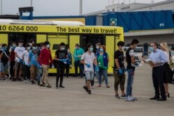 Deputy Migration Minister Giorgos Koumoutsakos, right, greets the 25 unaccompanied refugee children as they prepare to board a plane to Lisbon, Portugal at Athens International Airport, July 7, 2020.