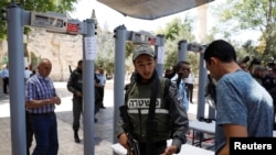 An Israeli border police officer asks to check the identity of a Palestinian man next to newly installed metal detectors at an entrance to the compound known to Muslims as Noble Sanctuary and to Jews as Temple Mount in Jerusalem's Old City, July 16, 2017.