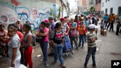 FILE - People wait in line for subsidized food staples, such as beans, rice, tuna and powdered milk, provided by the government program CLAP, which stands for Local Committees of Supply and Production, in Caracas, Venezuela, May 16, 2018.