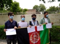 Afghans studying in India hold placards and stand outside the U.S. Embassy asking for help, in New Delhi, India, Aug. 28, 2021. The students say they aren't able to receive funds from Afghanistan after the Taliban takeover of the country.