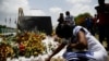 A woman lights a candle at a memorial outside the Presidential Palace in memory of slain President Jovenel Moise, in Port-au-Prince, Haiti, July 14, 2021, a week after Moise was assassinated at his home.