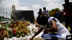 A woman lights a candle at a memorial outside the Presidential Palace in memory of slain President Jovenel Moise, in Port-au-Prince, Haiti, July 14, 2021, a week after Moise was assassinated at his home.