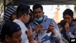 ARCHIVO - Migrantes reciben ayuda con la app CBPOne de un trabajador municipal en Tijuana, México, el martes 24 de enero de 2023 en Tijuana, México.