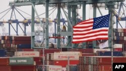 Chinese shipping containers are stored beside a U.S. flag after they were unloaded at the Port of Los Angeles in Long Beach, California on May 14, 2019. 
