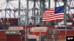 Chinese shipping containers are stored beside a U.S. flag after they were unloaded at the Port of Los Angeles in Long Beach, California on May 14, 2019. 
